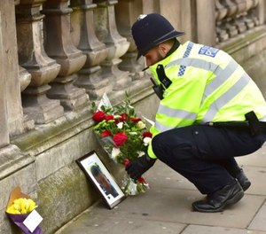 A police officer places flowers and a photo of fellow police officer Keith Palmer, who was killed in yesterdays attack, on Whitehall near the Houses of Parliament in London, Thursday March 23, 2017. (Dominic Lipinski/PA via AP)