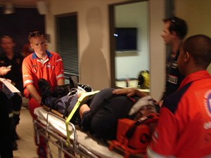 Paramedics wheeling a patient out strapped on a stretcher after injury
