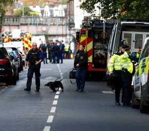 Police officers walk with a dog within a cordon near where an incident happened, that police say they are investigating as a terrorist attack, at Parsons Green subway station in London, Friday, Sept. 15, 2017. A bucket wrapped in an insulated bag caught fire on a packed London subway train Friday, sending commuters stampeding in panic at the height of the morning rush hour. (AP Photo/Kirsty Wigglesworth)
