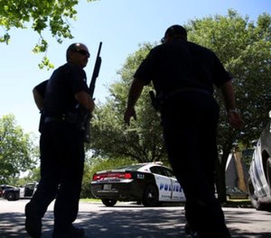 Dallas Police walk a neighborhood a block away from a shooting in Dallas, Monday, May 1, 2017. Authorities said a Dallas paramedic has been shot while responding to a shooting call. (AP Photo/LM Otero)