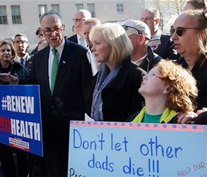 Jack McNamara, 9, right, holds a sign on behalf of his late father during a rally calling for the funding of the Zadroga Act.