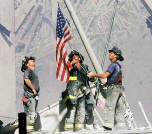 Firefighters raise a flag late in the afternoon on Tuesday, Sept. 11, 2001, in the wreckage of the World Trade Center towers in New York.