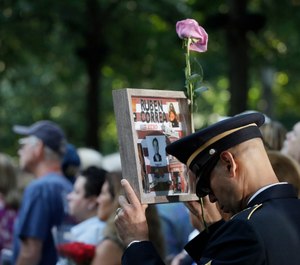 A man holds a photo of a victim during a ceremony marking the 18th anniversary of the attacks of Sept. 11, 2001, at the National September 11 Memorial, Wednesday, Sept. 11, 2019, in New York. (AP Photo/Mark Lennihan)