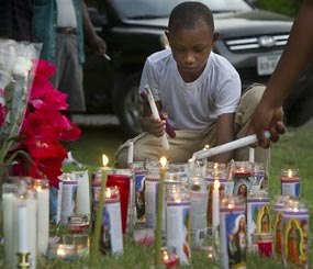 Darrel Brown, 8, lights candles at a makeshift memorial for Pearlie Golden during a vigil at Golden's home Wednesday, May 7, 2014, in Hearne, Texas.