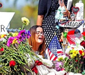Marjory Stoneman Douglas High School former student Ariana Gonzalez weeps at a cross of slain Marjory Stoneman Douglas coach Aaron Feis, on a hill honoring those killed, Friday, Feb. 23, 2018, in Parkland, Fla.