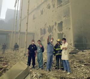 Medical and emergency workers, who are standing in front of the Millenium Hilton, look towards where the World Trade Center towers used to be, after the terrorist attack.