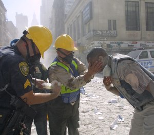 Police officers help rinse a man's eyes after the fall of the twin towers on September 11, 2001 in New York City.