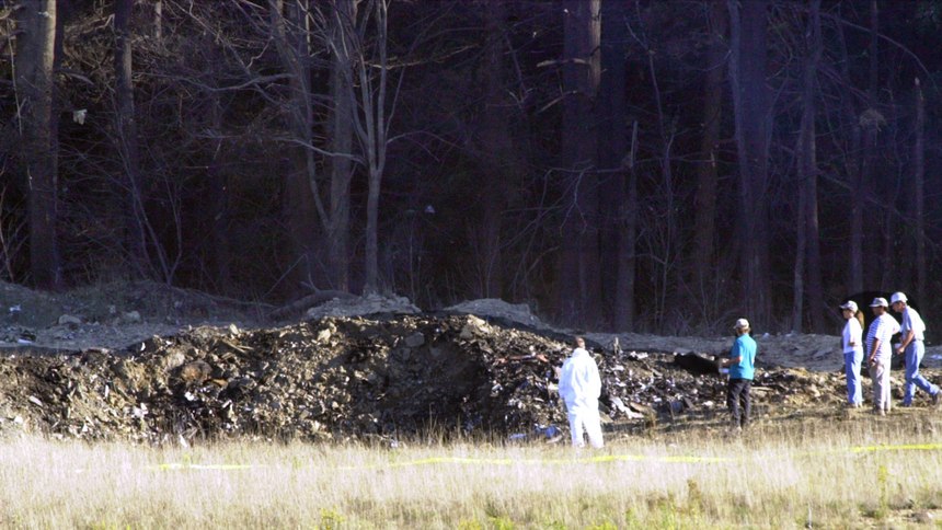 Emergency workers look at the crater created when United Airlines Flight 93 crashed near Shanksville, Pa.