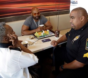Naomi Parham, left, talks with Miami Gardens police lieutenant Alonzo Moncur, right, during a Coffee with a Cop event, April 27, 2016, in Miami Gardens, Fla.