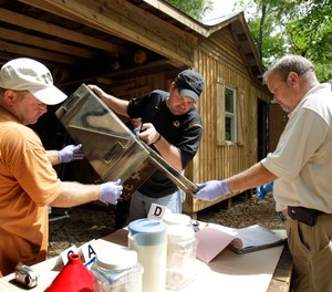 In this Sept. 2, 2010 file photo, Franklin County Detective Jason Grellner, center, sorts through evidence with Detective Darryl Balleydier, left, and reserve Officer Mark Holguin during a raid of a suspected meth house in Gerald, Mo.