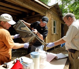 In this Sept. 2, 2010 file photo, Franklin County Detective Jason Grellner, center, sorts through evidence with Detective Darryl Balleydier, left, and reserve Officer Mark Holguin during a raid of a suspected meth house in Gerald, Mo.