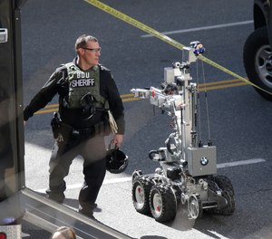 A King County Sheriff bomb disposal unit officer walks near a robotic device near the scene of a shooting involving several police officers in downtown Seattle, Thursday, April 20, 2017.
