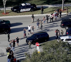 In this Feb. 14, 2018 file photo, students hold their hands in the air as they are evacuated by police from Marjory Stoneman Douglas High School in Parkland, Fla., after a shooter opened fire on the campus.