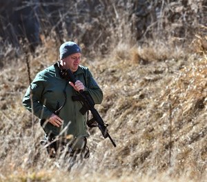 A law enforcement officer searches a wooded area for a suspect involved in a shooting at a Central Michigan University residence hall on Friday, March 2, 2018 in Mt. Pleasant, Mich. (Matthew Dae Smith/Lansing State Journal via AP)