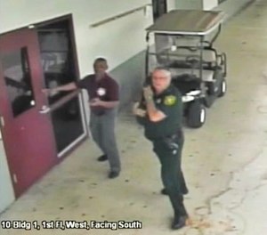 This Feb. 14, 2018 frame from security video provided by the Broward County Sheriff's Office shows deputy Scot Peterson, right, outside Marjory Stoneman Douglas High School in Parkland, Fla. The video released Thursday, March 15, shows Peterson going toward the high school building while a gunman massacred 17 students and staff members, but stayed outside with his handgun drawn. (Courtesy of the Broward County Sheriff's Office via AP)
