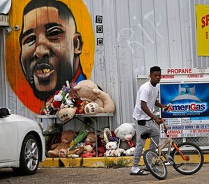 In this June 27, 2017 photo, Ronald Smith gets on his bicycle after stopping at the Triple S Food Mart, where Alton Sterling was shot by police one year ago, in Baton Rouge, La.