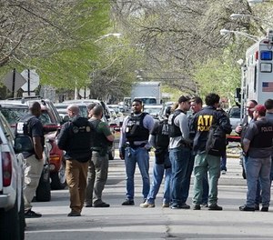 In this May 4, 2018 file photo Police from various agencies investigate the scene where a Bureau of Alcohol, Tobacco, Firearms and Explosives agent was shot, May 4, 2018, in Chicago. A law enforcement official says a suspect has been arrested in the shooting. (AP Photo/Teresa Crawford File)