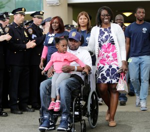 New York Police Detective Dalsh Veve, center, leaves the Kessler Institute for Rehabilitation with his wife, Esther, right, and daughter Dashi, Monday, May 7, 2018, in West Orange, N.J. Veve was critically injured in June 2017 when he was dragged by a driver in a stolen car.