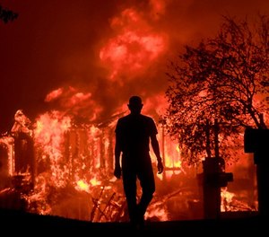 In this Oct. 9, 2017, file photo, Jim Stites watches part of his neighborhood burn in Fountaingrove, Calif.
