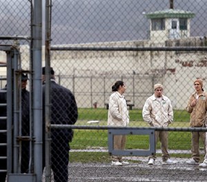 In this file photo taken Jan. 28, 2016, inmates mingle in a recreation yard in view of COs, left, at the Monroe Correctional Complex in Monroe, Wash.