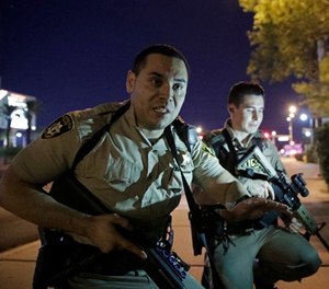 In this Oct. 1, 2017, file photo, police officers advise people to take cover near the scene of the Route 91 Harvest Music Festival mass shooting. (AP Photo/John Locher, File)