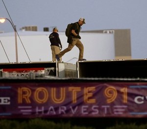 In this Oct. 3, 2017, file photo, FBI agents walk on the roof of boxes inside the concert grounds where a mass shooting occurred in Las Vegas.