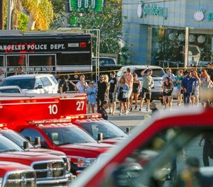Los Angeles Police SWAT officers escort a group of people who were held for their safety by police across businesses surrounding a Trader Joe's supermarket, after a gunman held dozens of people hostage inside the store before surrendering to police in Los Angeles Saturday, July 21, 2018. (AP Photo/Damian Dovarganes)