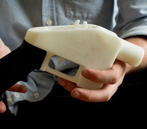 In this May 10, 2013, file photo, Cody Wilson holds what he calls a Liberator pistol that was completely made on a 3-D-printer at his home in Austin, Texas.