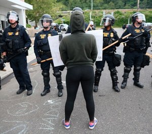 In this June 28, 2018, file photo, Department of Homeland Security officers take action to reopen Portland's Immigration and Customs Enforcement headquarters in Portland, Ore.