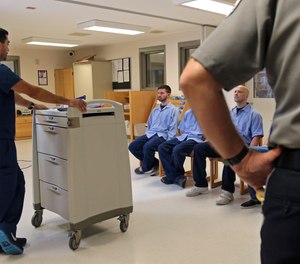 In this July 23, 2018, photo, several Franklin County Jail inmates seated at right are watched by nurse Brian Toia, left, and a corrections officer after they received their daily doses of buprenorphine, a drug which controls heroin and opioid cravings.
