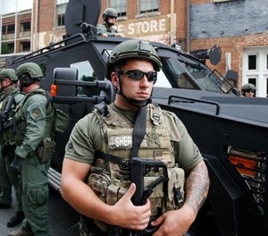 Members of a SWAT team keep an eye on demonstrators marking the one year anniversary of the Unite The Right rally in Charlottesville, Va., Sunday, Aug. 12, 2018. (AP Photo/Steve Helber)