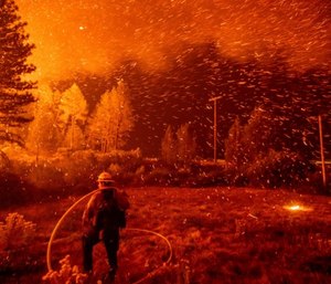 Embers fly above a firefighter as he works to control a backfire as the Delta Fire burns in the Shasta-Trinity National Forest, Calif., on Thursday, Sept. 6, 2018. (AP Photo/Noah Berger)