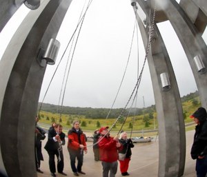 In this photo made with a fisheye lens, Tom Ridge the First U.S. Secretary of Homeland Security, and 43rd governor of Pennsylvania, left, joins in with some of the family, friends and volunteer representatives for the first ringing of the chimes at the dedication of the 93-foot tall Tower of Voices on Sunday, Sept. 9, 2018 at the Flight 93 National Memorial in Shanksville, Pa. The tower contains 40 wind chimes representing the 40 people that perished in the crash of Flight 93 in the terrorist attacks of Sept. 11, 2001. (AP Photo/Keith Srakocic, Pool)