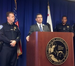 California Attorney General, Xavier Becerra, at podium, and other officials announce indictments of 32 members of purported street gangs on charges of stealing more than $1 million. (AP Photo/Don Thompson)