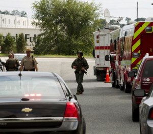 Police officers patrolled the area in the industrial business park where a shooter killed three people Thursday. (AP Photo/Jose Luis Magana)