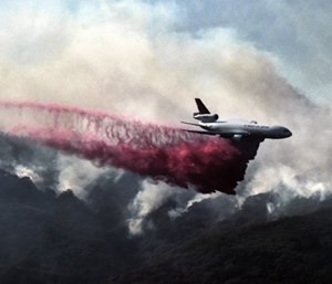 A firefighting DC-10 makes a fire retardant drop over a wildfire in the mountains near Malibu Canyon Road in Malibu, Calif. (Photo/AP)