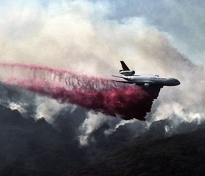 A firefighting DC-10 makes a fire retardant drop over a wildfire in the mountains near Malibu Canyon Road in Malibu, Calif. (Photo/AP)