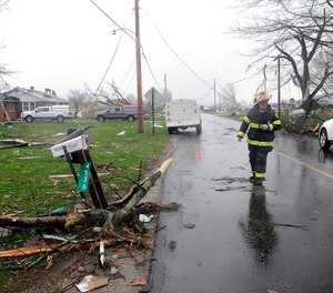 A Shelby firefighter walks down Plymouth Springmill Road just south of the intersection of Ohio Route 96, past severe storm damage to homes in Shelby, Ohio, Sunday, April 14, 2019. (Tom E. Puskar/The Times Gazette via AP)