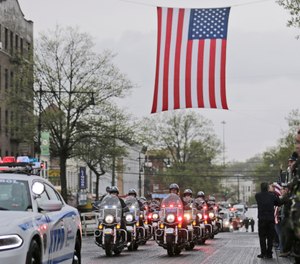 A procession escorting the body of Staff Sgt. Christopher Slutman arrives to a funeral home in the Bronx borough of New York, Monday, April 22, 2019. Firefighters in three states are honoring the U.S. Marine and New York City firefighter who was killed by a roadside bomb in Afghanistan. (AP Photo/Seth Wenig)