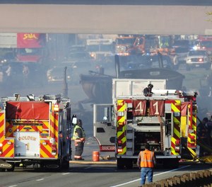 In this Thursday, April 25, 2019 photo, emergency crews work at the scene of a deadly collision on Interstate 70 near the Colorado Mills Parkway in Lakewood, Colo. On Friday, police said the truck driver blamed for causing the fatal pileup involving over two dozen vehicles has been arrested on vehicular homicide charges. (Hyoung Chang/The Denver Post via AP)