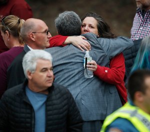 Parents hug as they wait for their children at a recreation center where students were reunited with their parents Tuesday, May 7, 2019, in Highlands Ranch, Colo.