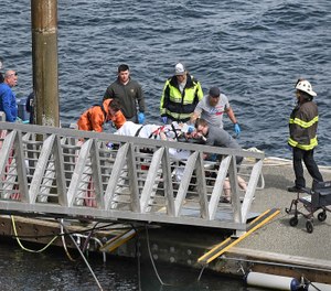 Emergency response crews transport an injured passenger to an ambulance at the George Inlet Lodge docks, Monday, May 13, 2019, in Ketchikan, Alaska. The passenger was from one of two sightseeing planes reported down in George Inlet early Monday afternoon and was dropped off by a U.S. Coast Guard 45-foot response boat. (Dustin Safranek/Ketchikan Daily News via AP)