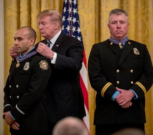 President Donald Trump awards Fire Captain Dustin Moore, right, and Firefighter Paramedic Andrew Freisner, left, of the Lenexa Fire Department, Kansas, the Public Safety Officer Medal of Valor at a ceremony in the East Room of the White House in Washington, Wednesday, May 22, 2019.