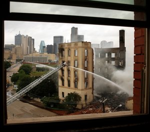 Dallas firefighters pour water on the destroyed historic Ambassador hotel just south of downtown Dallas, Tuesday, May 28, 2019. Over 100 firefighters responded to the four-alarm fire. (Tom Fox/The Dallas Morning News via AP)