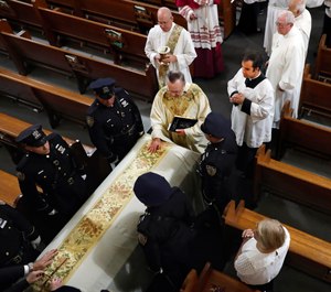 Rev. John P. Harrington blesses the casket during the funeral ceremony for Detective Luis Alvarez, at Immaculate Conception Church, in the Queens borough of New York. Alvarez, 53, who died after a three-year battle with colorectal cancer, fought until his final days for the extension of the Sept. 11 Victim Compensation Fund. (Photo AP/Richard Drew, Pool)