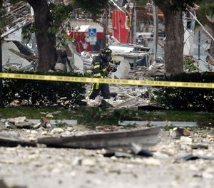 A firefighter walks through the remains of a building after an explosion. Several people were injured after a vacant pizza restaurant exploded in the South Florida shopping plaza Saturday, according to police. The restaurant was destroyed, and nearby businesses were damaged.