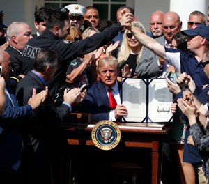 President Donald Trump holds up the signed H.R. 1327 bill, an act ensuring that a victims' compensation fund related to the Sept. 11 attacks never runs out of money, in the Rose Garden of the White House.
