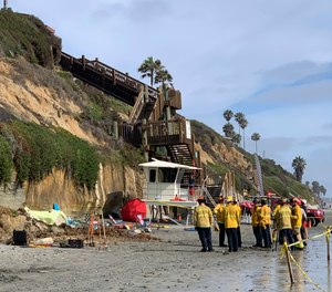 Lifeguards and search and rescue personnel work at the site of a cliff collapse at a popular beach in Encinitas, Calif.