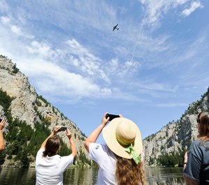 Spectators use cell phones to capture Miss Montana fly over and drop wreaths in the Gates of the Mountains in Montana. (Photo/Thom Bridge, Independent Record via AP)