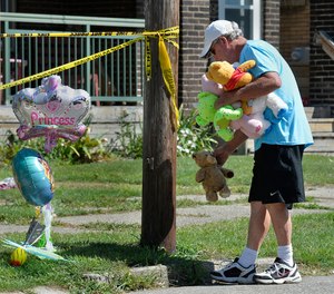 Paul Laughlin, 57, places stuffed animals outside a home where multiple people died in an early-morning fire. (Photo/Greg Wohlford, Erie Times-News via AP)